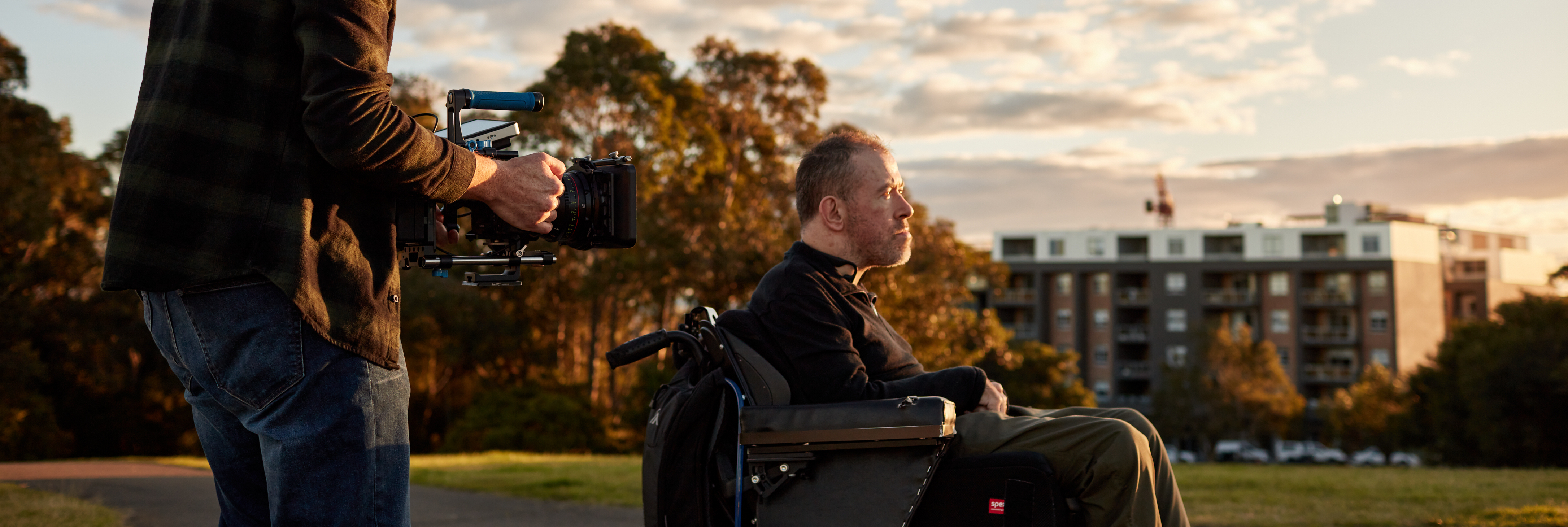 A man using a wheelchair being filmed outdoors